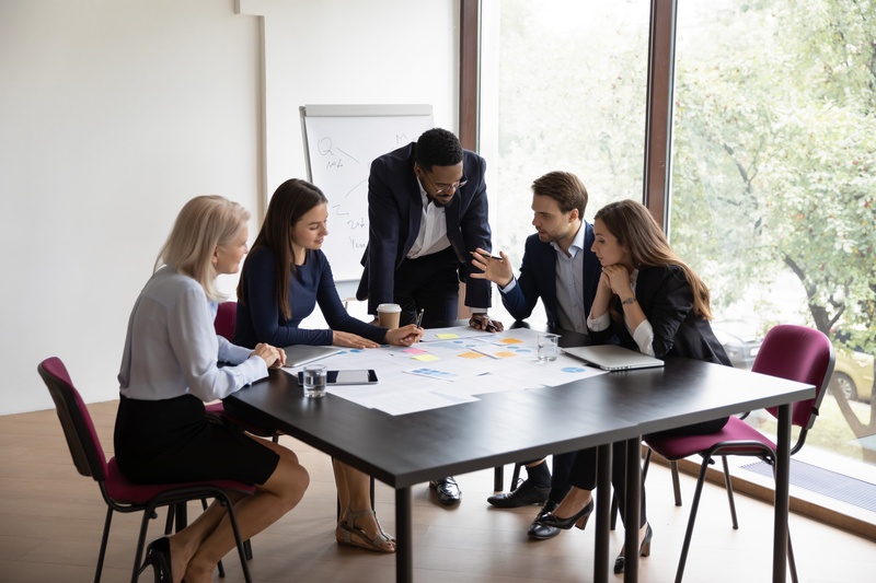 A team of professionals in a boardroom reviewing business charts and a flowchart, symbolising strategic planning and operational excellence.