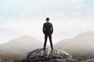 A business leader standing on a mountain peak, symbolising visionary leadership.