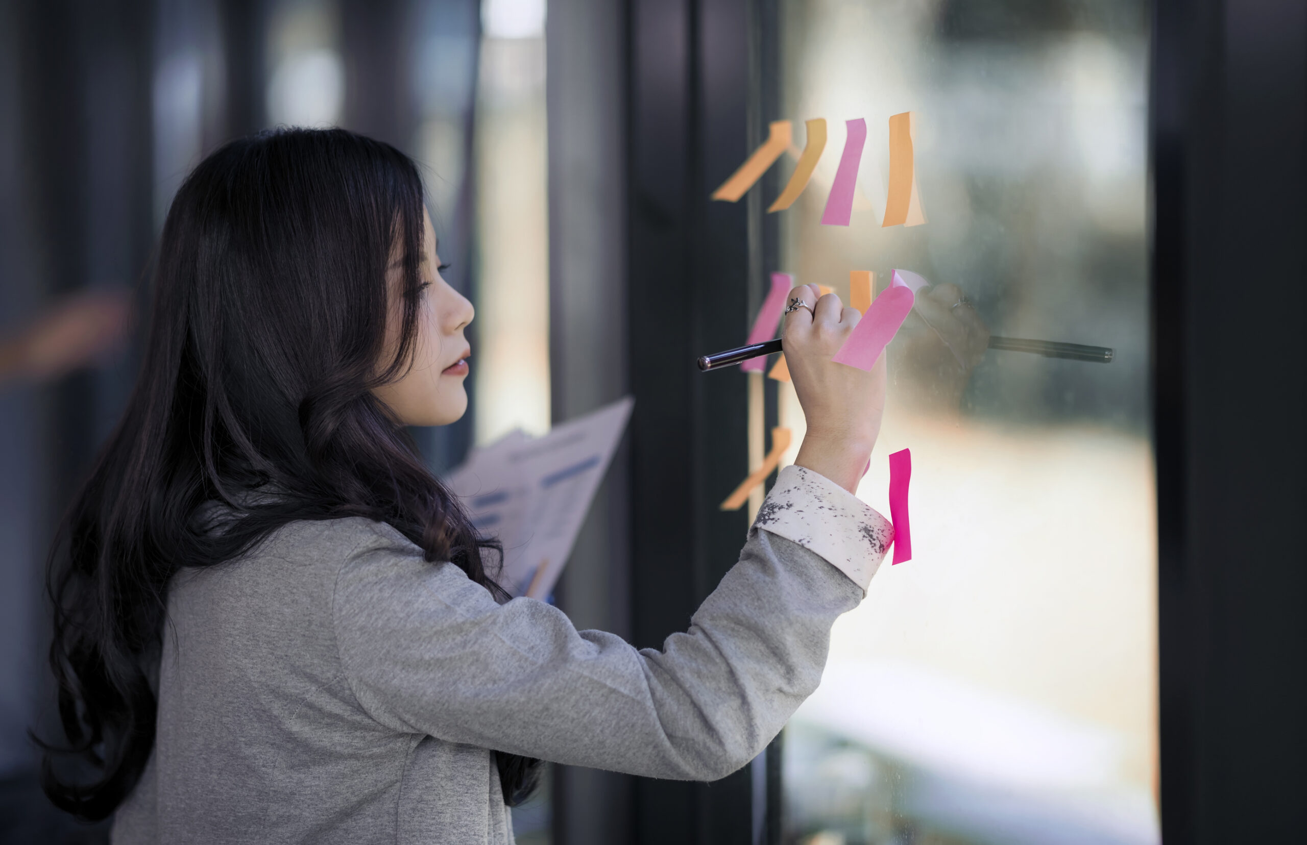 A person arranging sticky notes into categories on a whiteboard, representing task organisation.