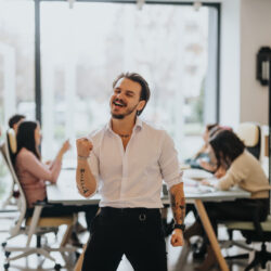 A cheerful entrepreneur sitting at a tidy desk, celebrating the completion of tasks with a fist pump