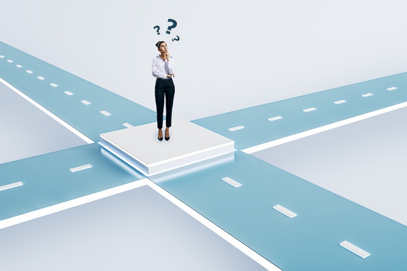 A businessperson standing at a crossroads, looking at directional signs, symbolising decision-making and change.