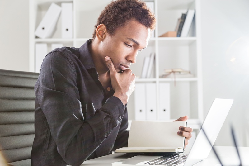 A professional reading a book and taking notes, symbolising continuous learning and self-improvement.